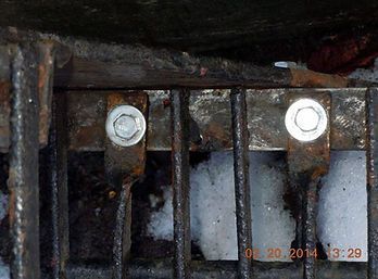 A close up of a metal grate with screws on it.