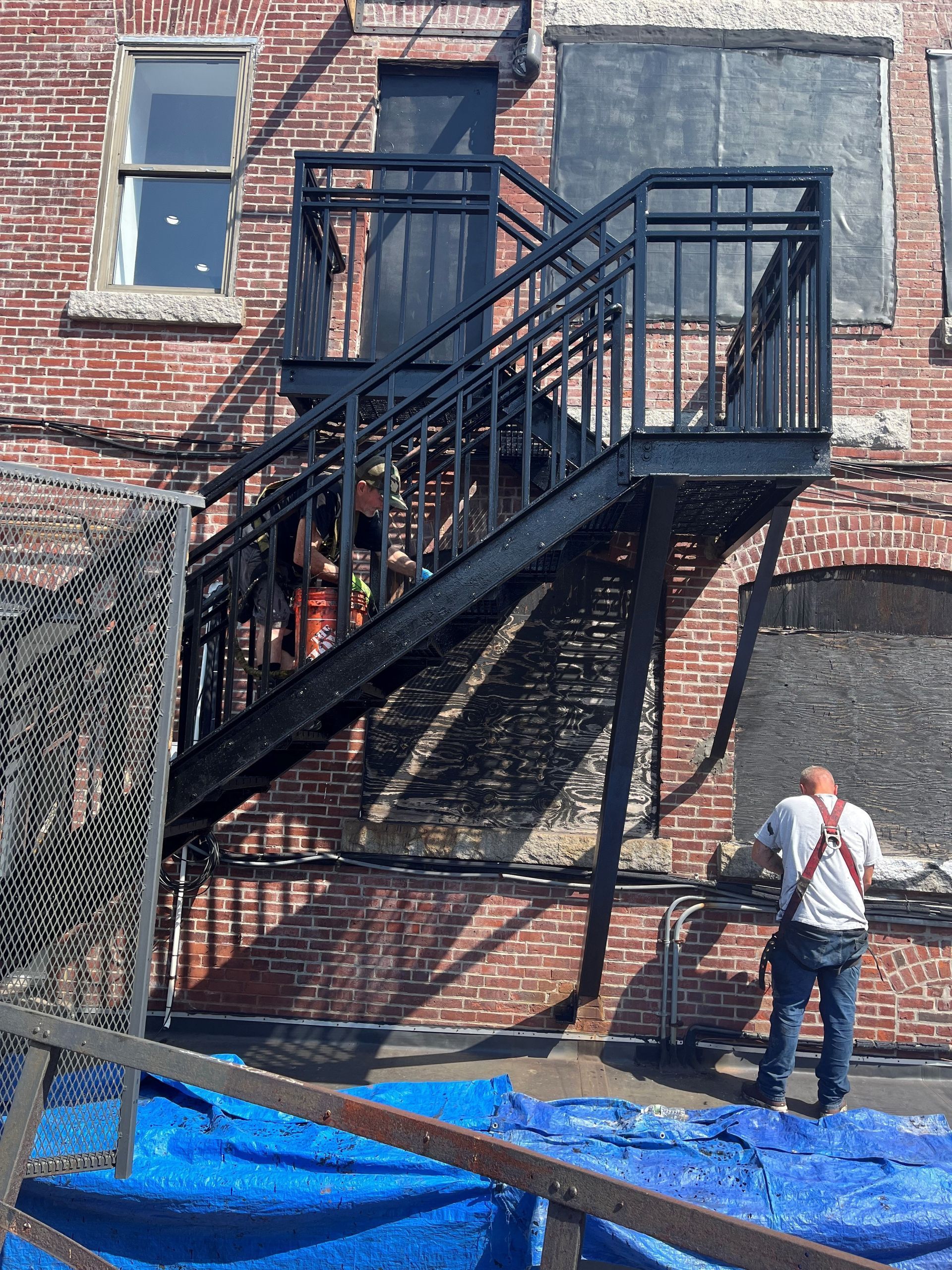 A man is standing next to a fire escape on the side of a brick building