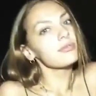 Mujer con cabello largo y rubio, con top negro y pendientes de aro, mirando a la cámara.