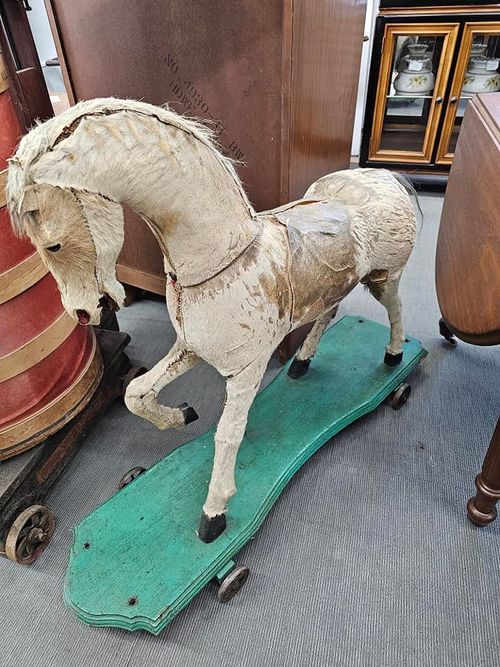 A wooden rocking horse is sitting on a green board.