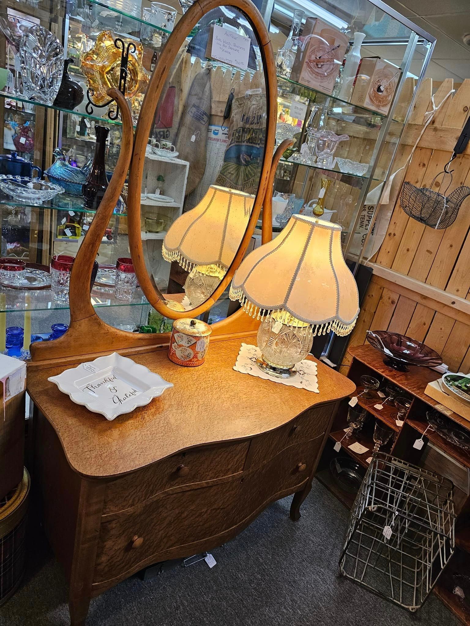 A dresser with a mirror and two lamps on it in a store.