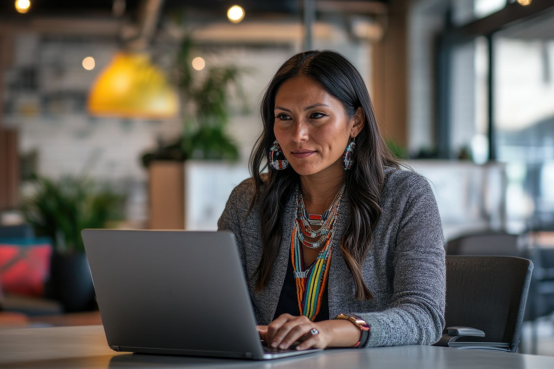 A professional seated at a wooden desk discusses documents with a client in an office with a map on the wall.