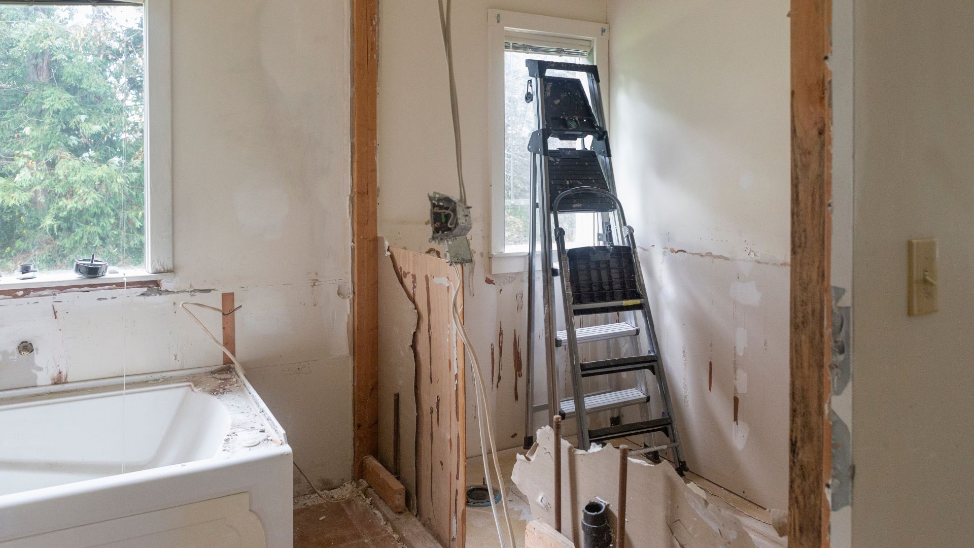 A bathroom under construction with a bathtub and a ladder.