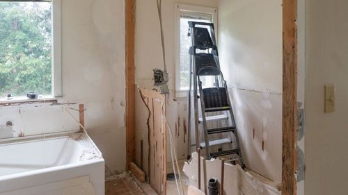 A bathroom under construction with a bathtub and a ladder.