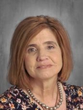 A close up of a woman wearing a necklace and a floral shirt.