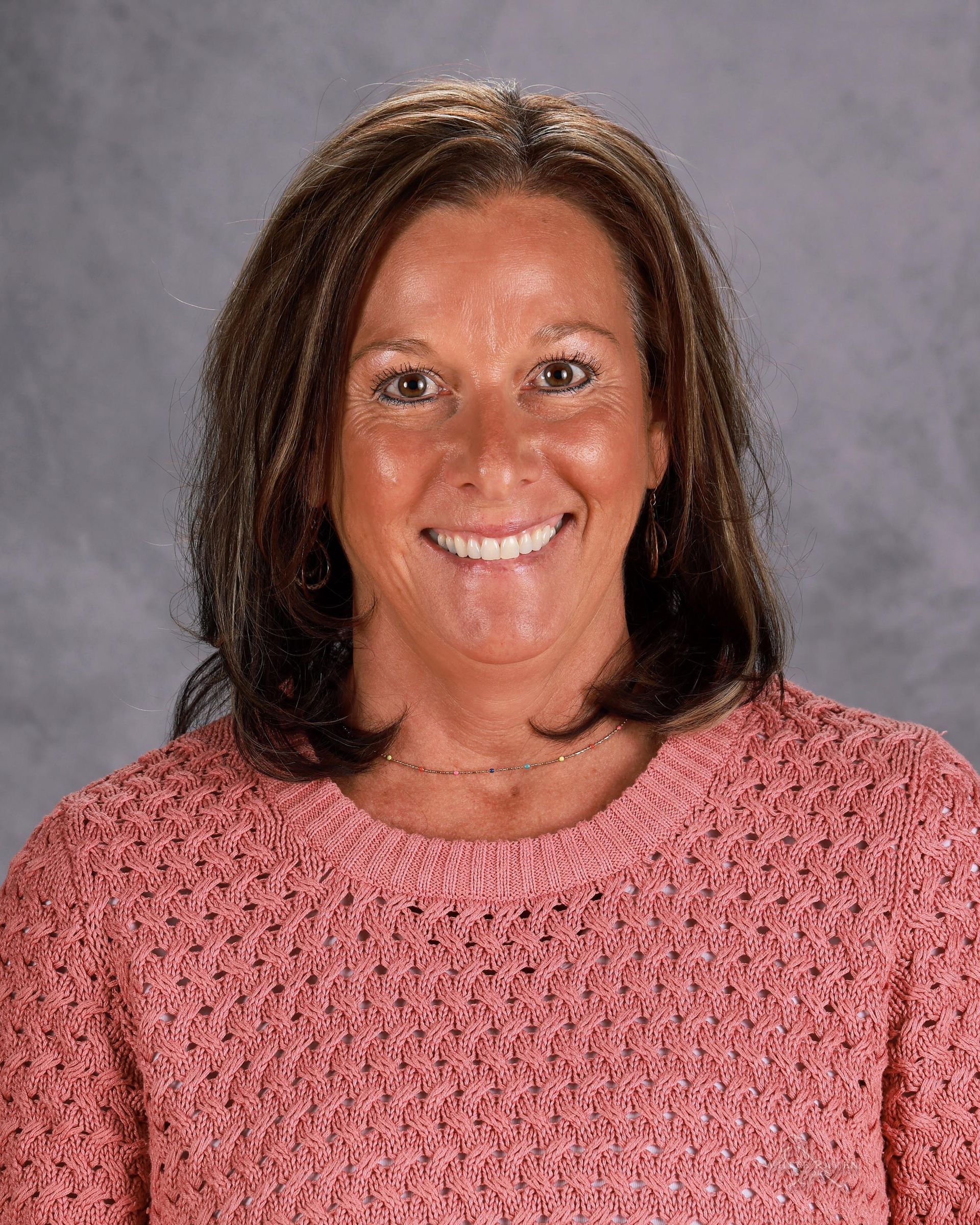 A woman in a white shirt and black jacket is smiling for the camera.
