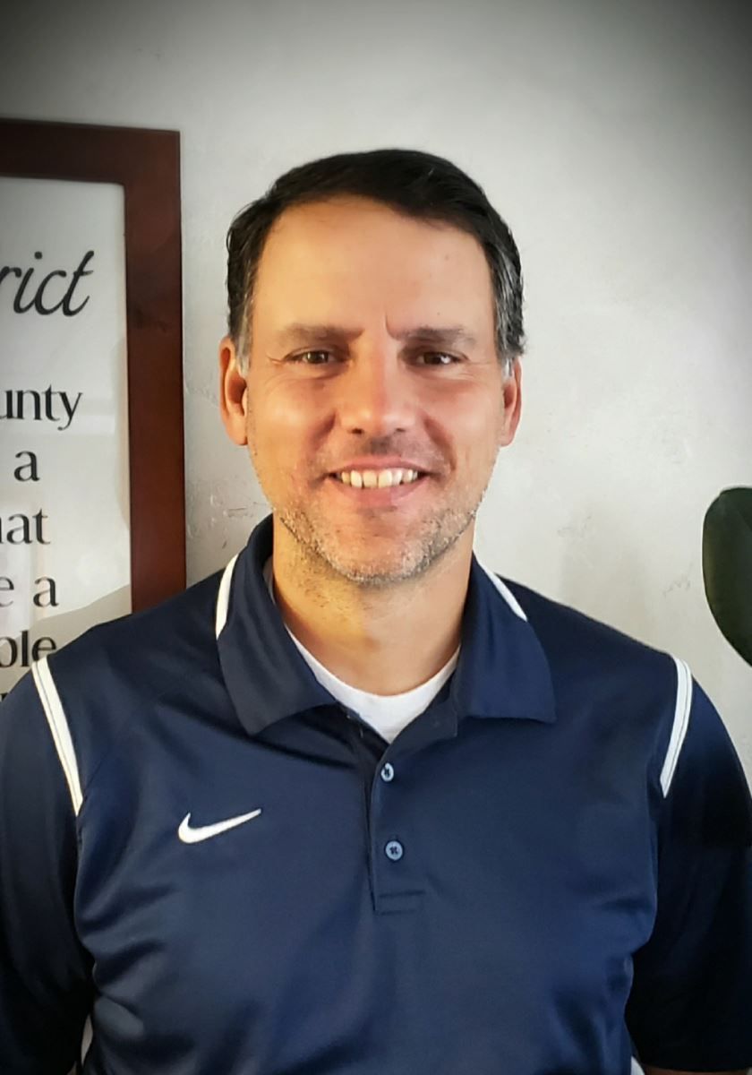 A man wearing a blue nike shirt smiles for the camera
