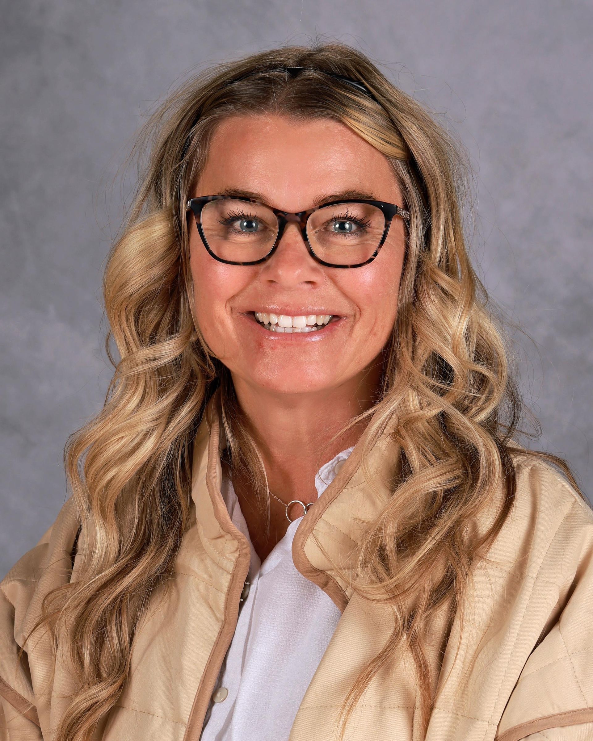 A woman wearing glasses and an orange shirt is smiling for the camera.