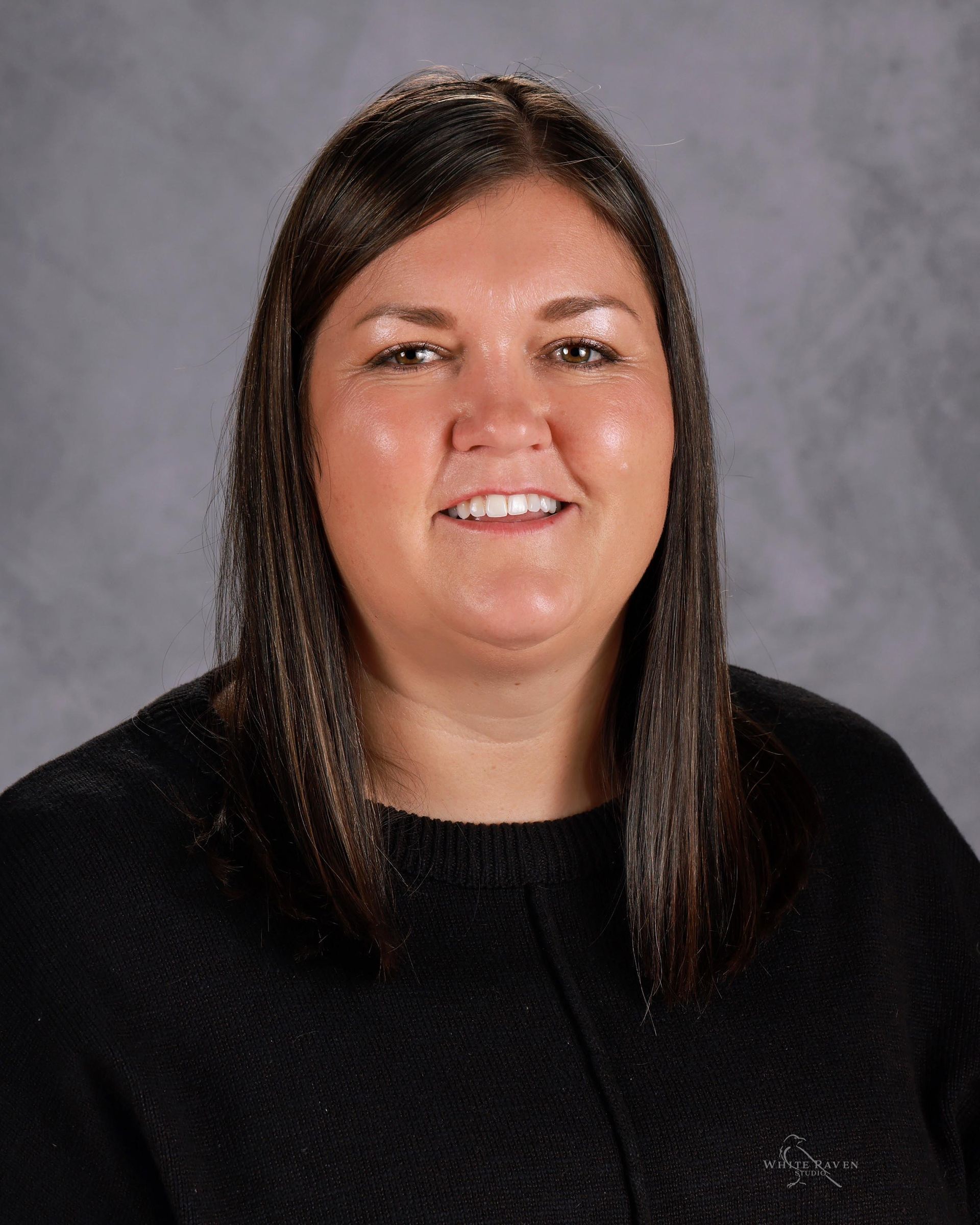 A woman with long brown hair is smiling for the camera.