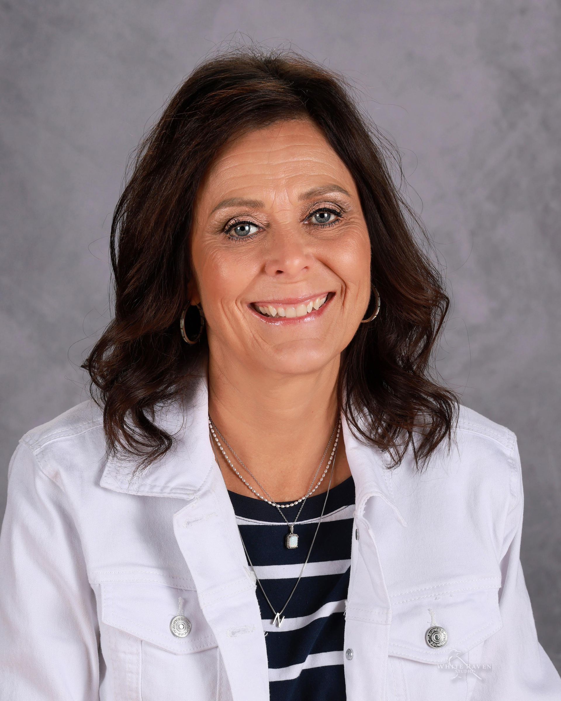 A woman in a blue shirt is smiling for the camera.