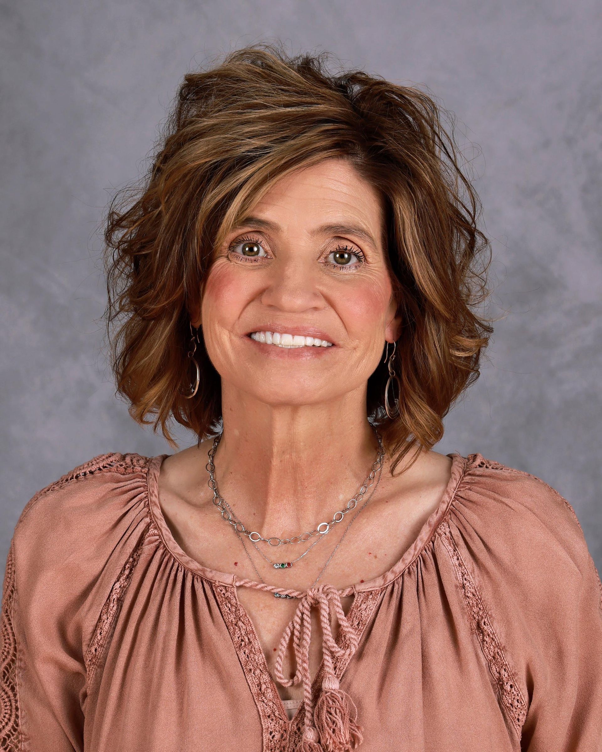 A close up of a woman wearing a necklace and a floral shirt.