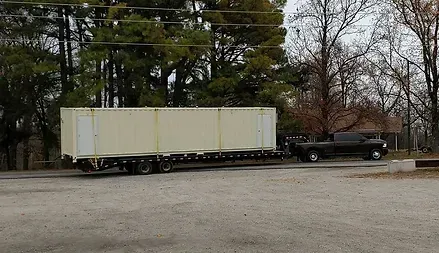 a truck is pulling a container on a trailer in a parking lot .