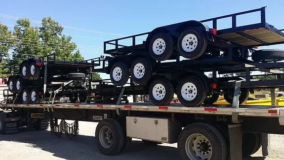 a trailer with a lot of trailers on it is parked in a parking lot .