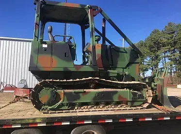 a camouflaged bulldozer is sitting on top of a trailer .