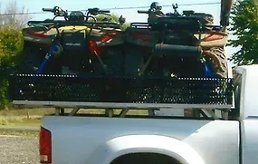 two atvs are sitting in the back of a truck .