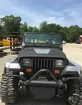 a black jeep is parked in a dirt lot .