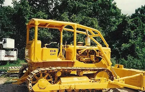 a yellow bulldozer is parked in front of trees