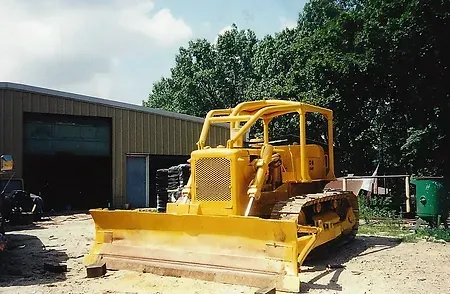 a yellow bulldozer is parked in front of a garage