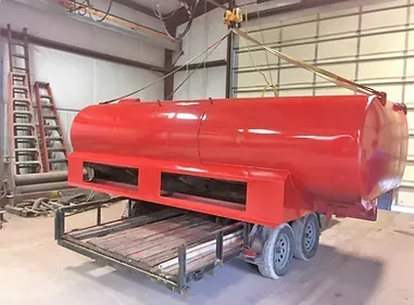 a large red tank is sitting on a trailer in a garage .