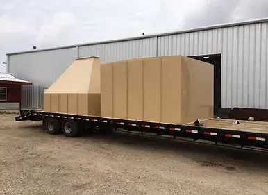 a trailer with a large box on it is parked in front of a building .