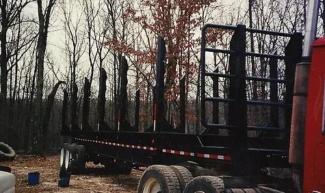 a red truck is parked in a field with trees in the background
