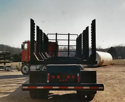 a red truck with a black trailer is parked in a dirt field