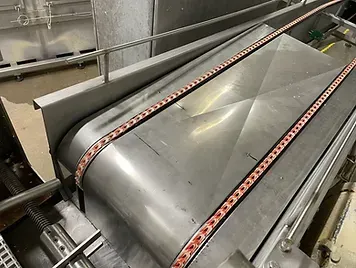 a stainless steel conveyor belt is being used in a factory .