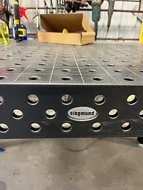 a metal table with holes in it is sitting on top of a concrete floor .