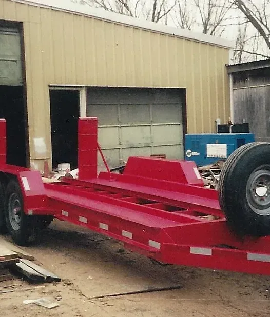 a red trailer is parked in front of a garage