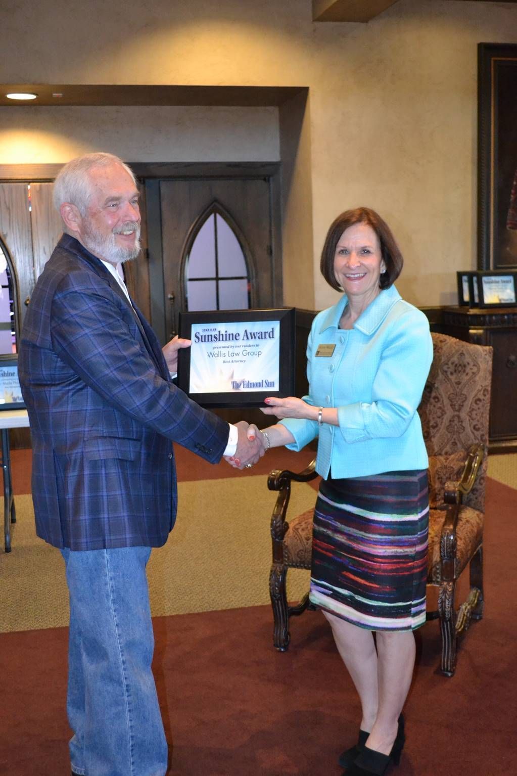 A man and woman are shaking hands and the woman is holding a certificate.