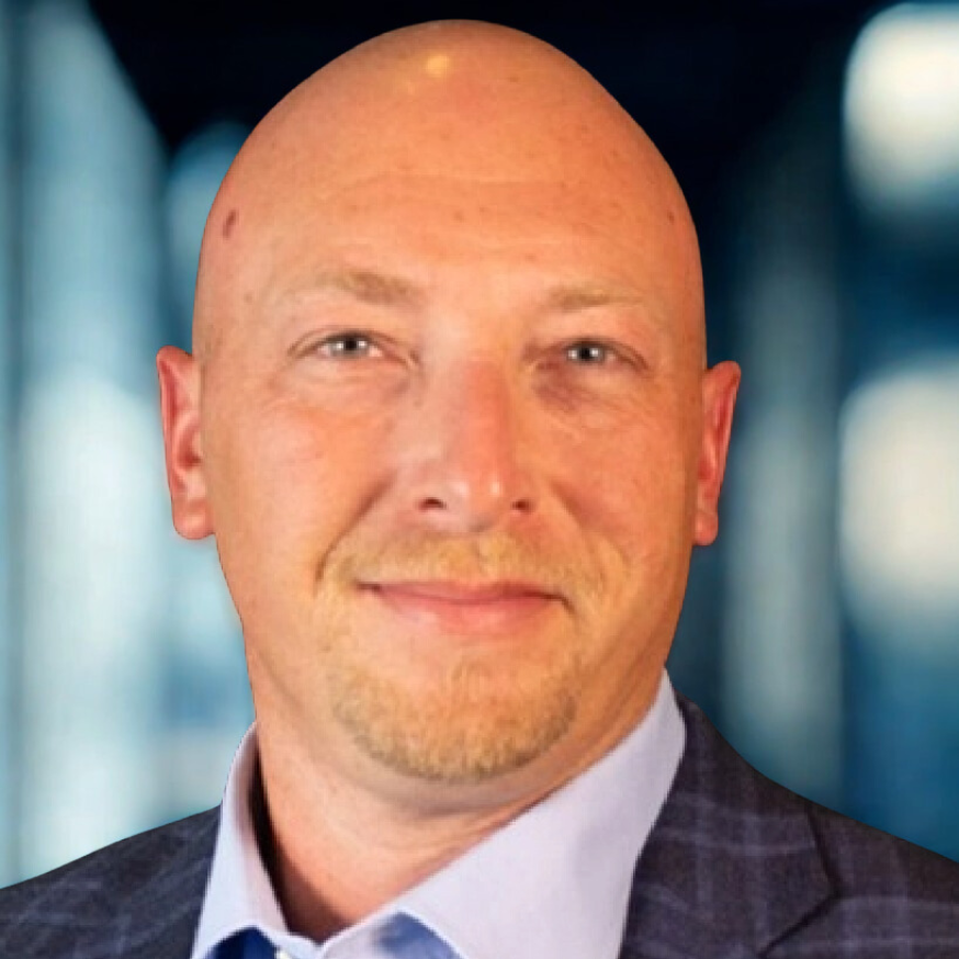 Bald man with a goatee in a blue blazer smiling. Black background.