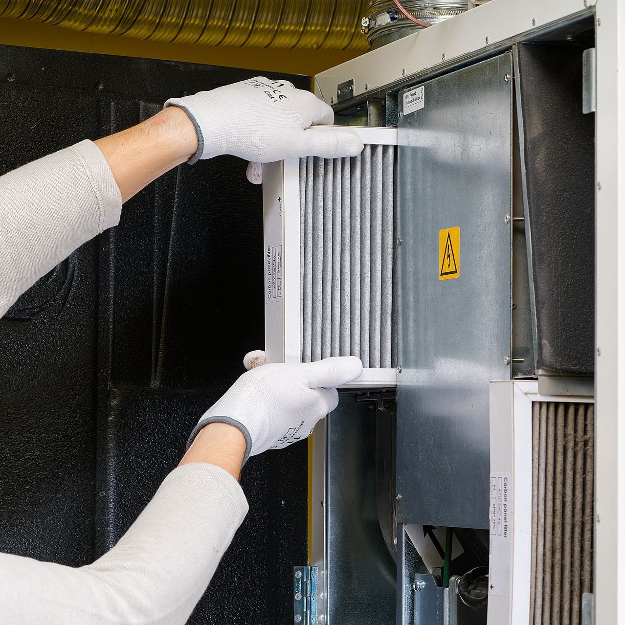 A person wearing white gloves removes a filter from a machine