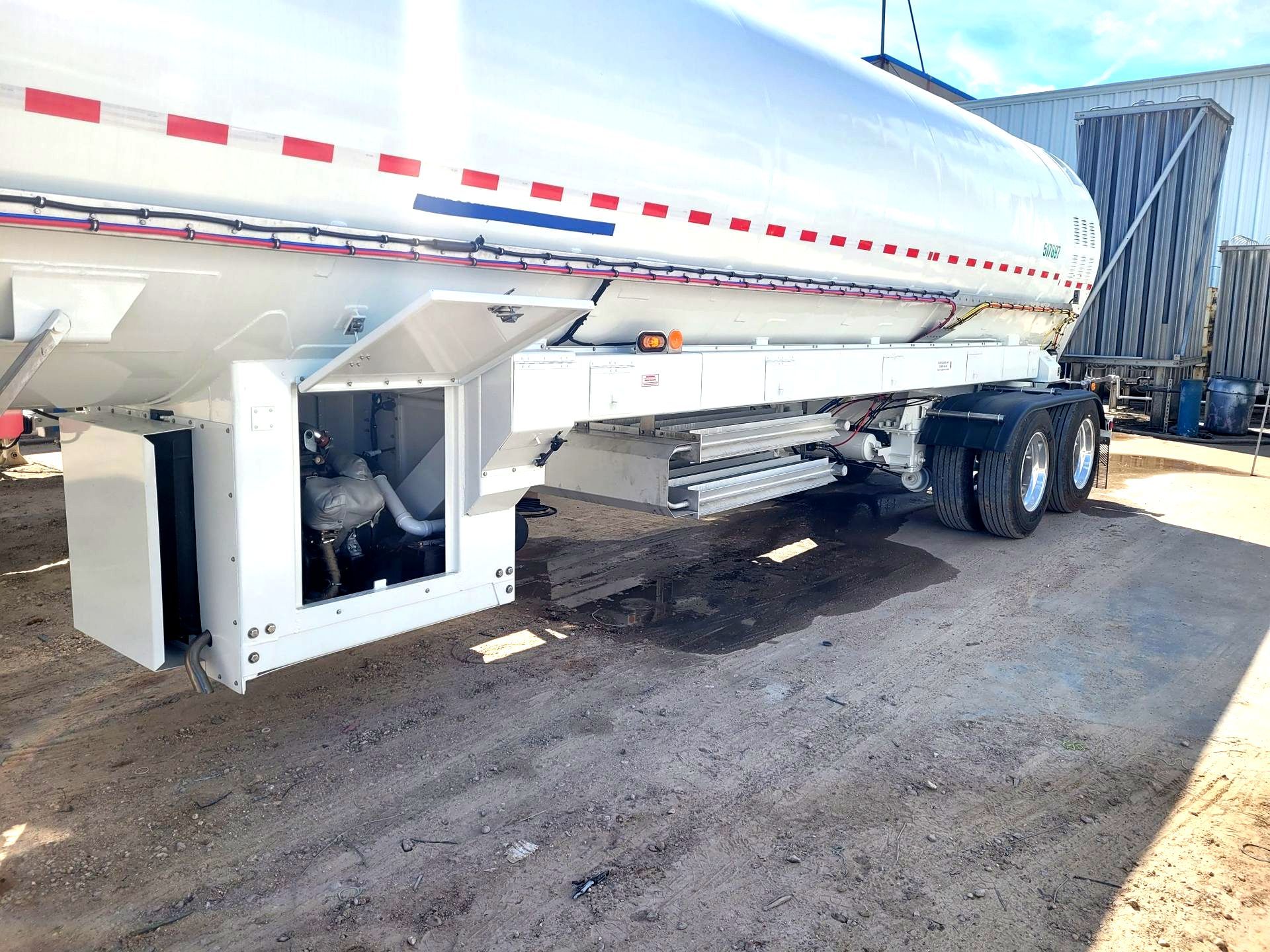 A white semi truck is parked in a dirt lot.