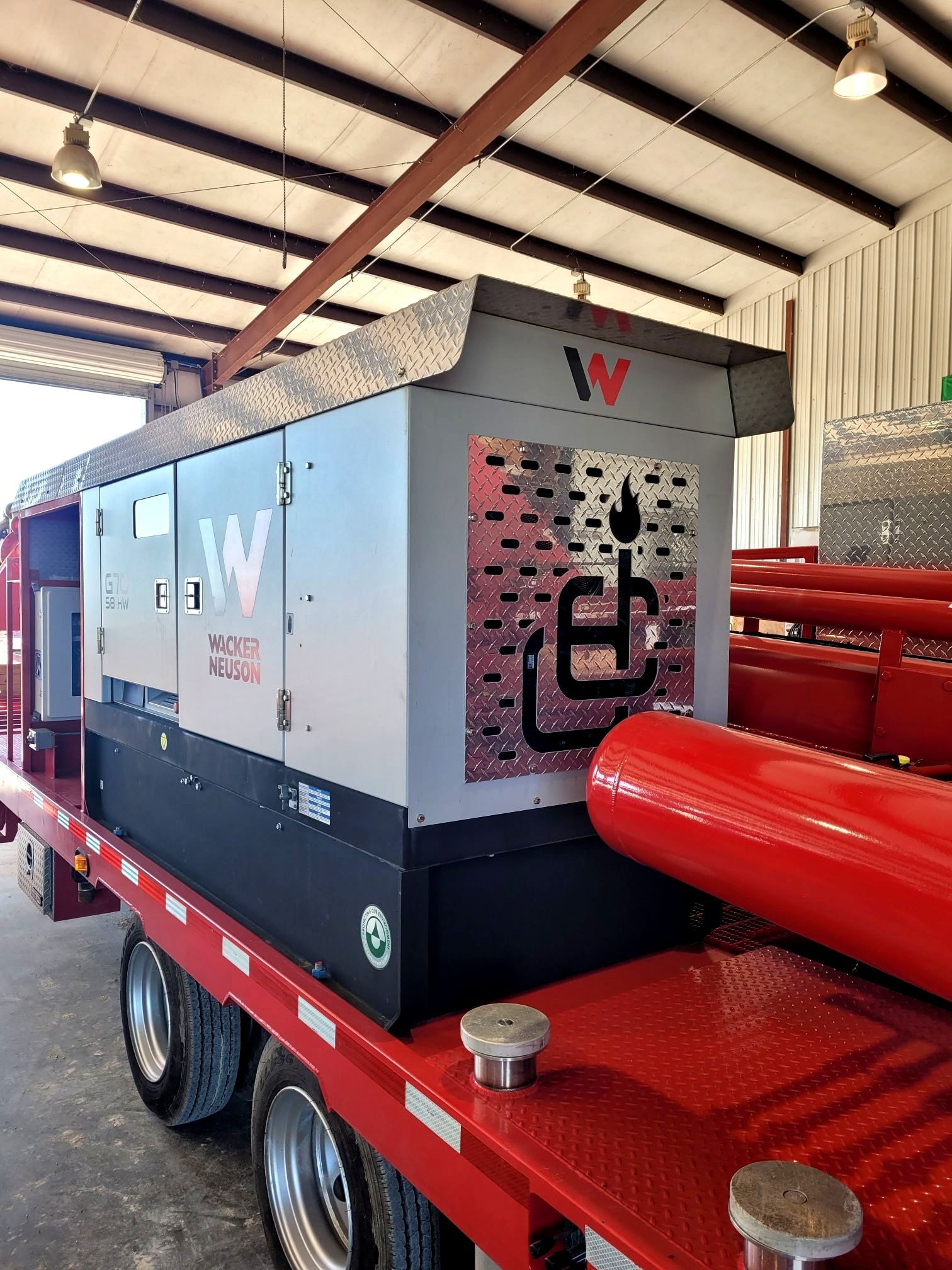 A red truck with a generator on the back is parked in a garage.