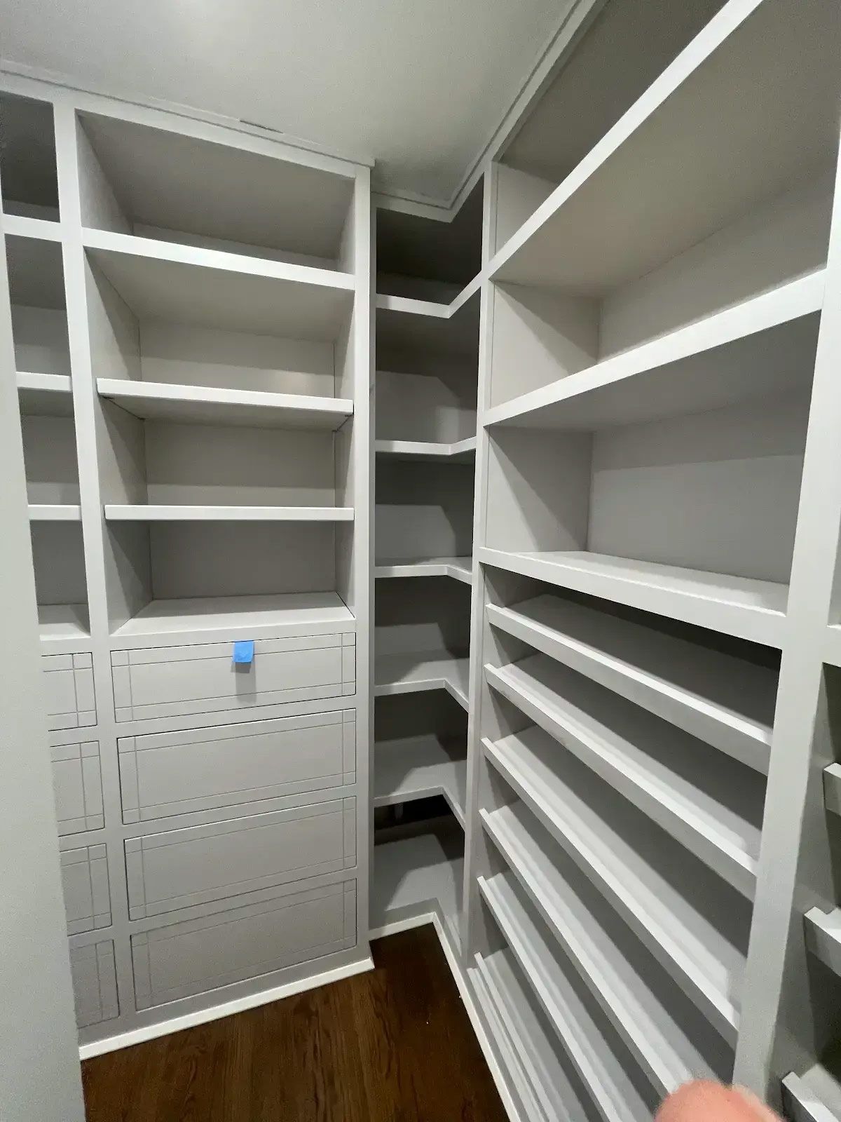 A walk in closet with lots of shelves and drawers