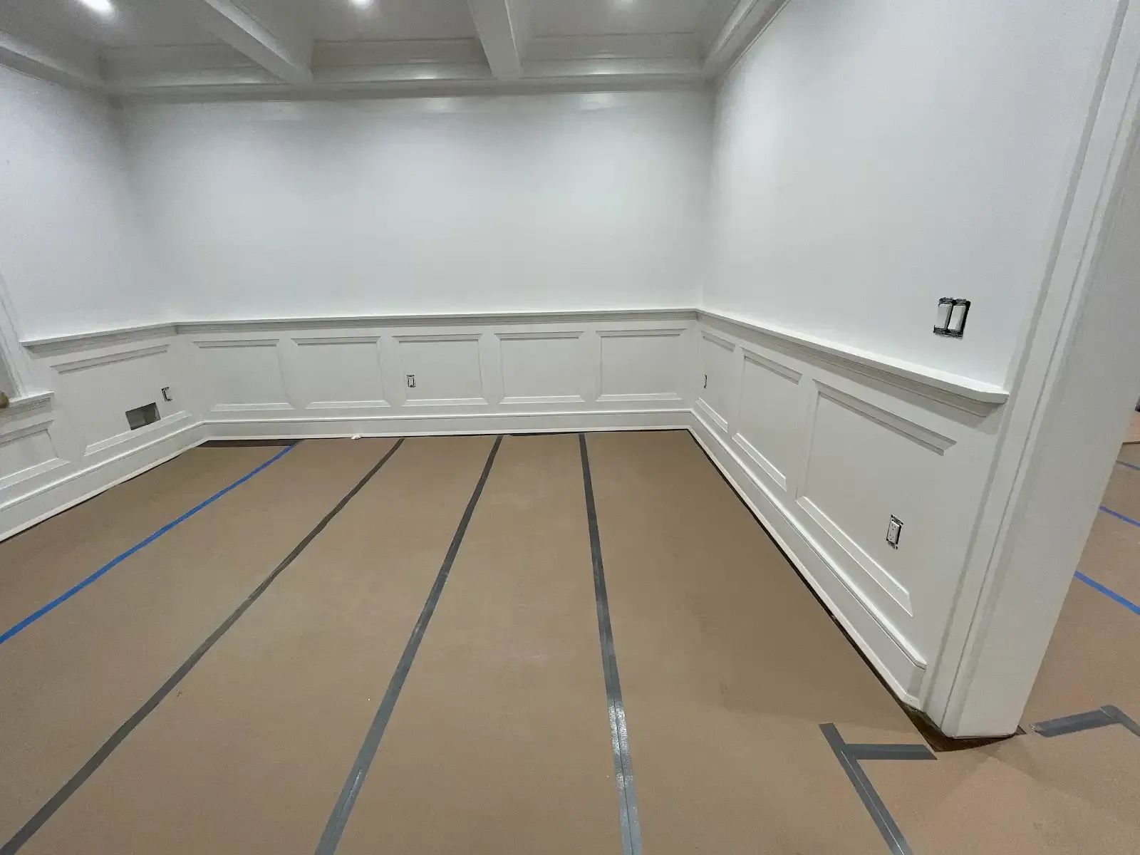 A room with white walls and blue tape on the floor
