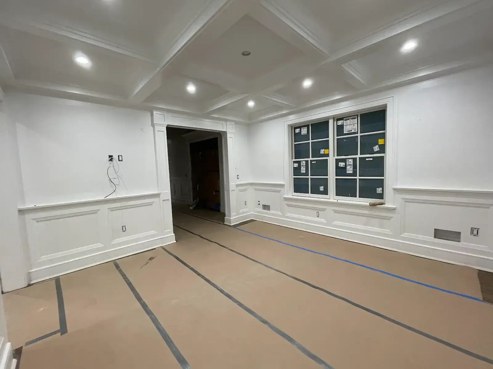 A large empty room with white walls and a coffered ceiling