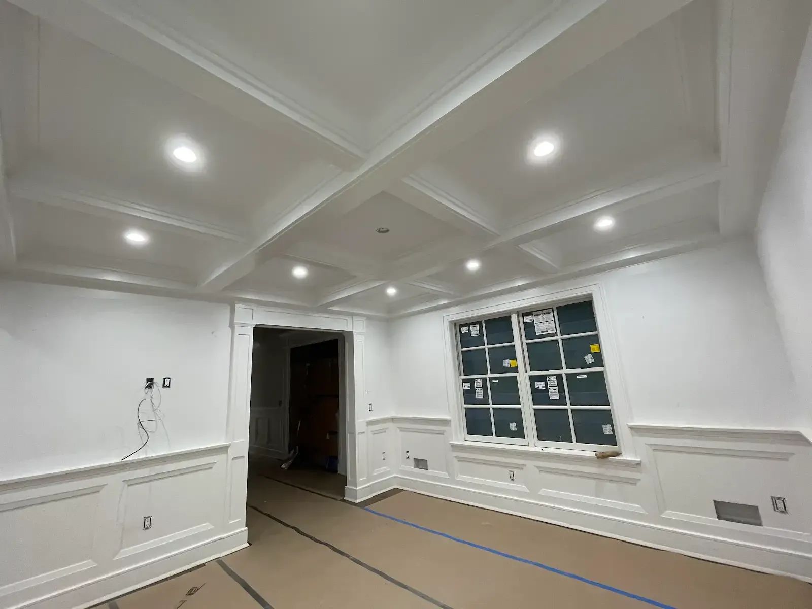 A living room with a coffered ceiling and a window
