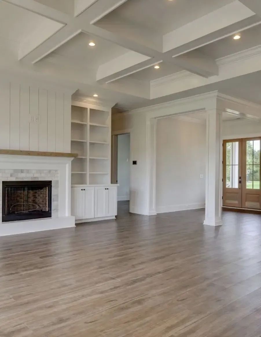 An empty living room with hardwood floors and a fireplace