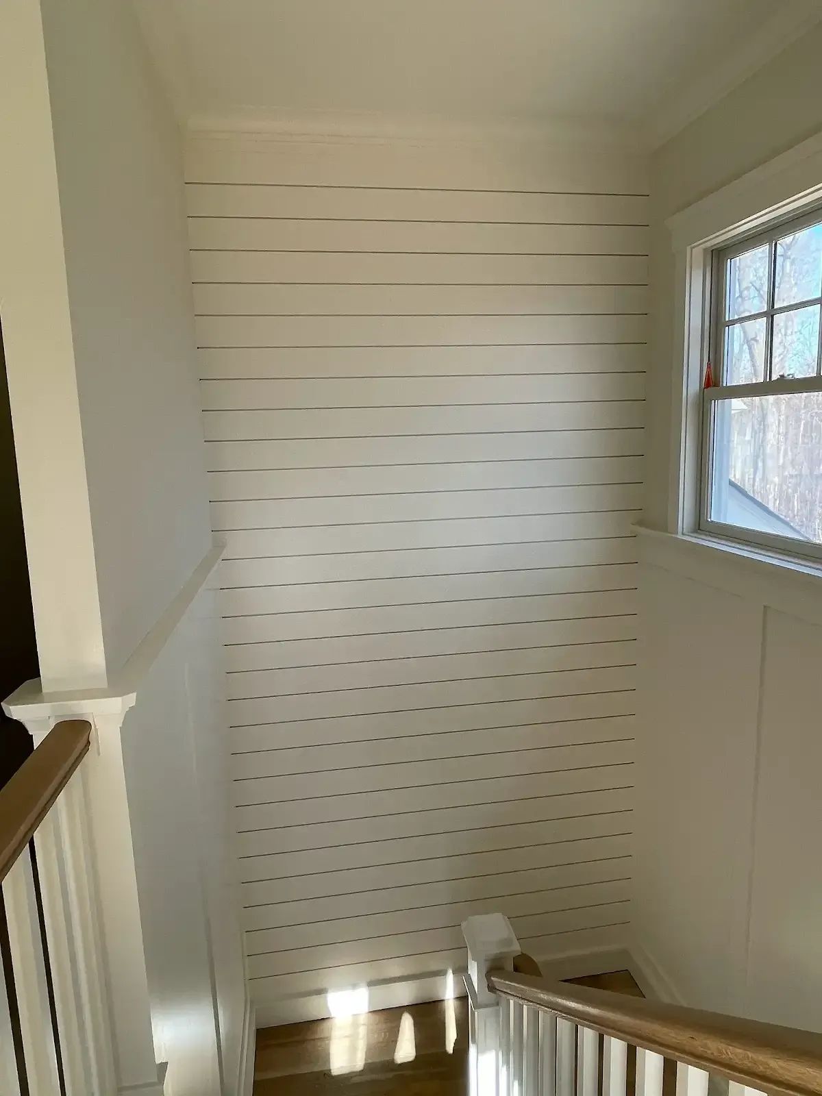 A staircase with a white wall and a window
