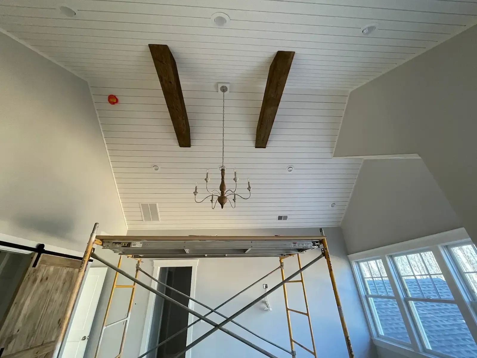 A room with a scaffolding and a chandelier hanging from the ceiling