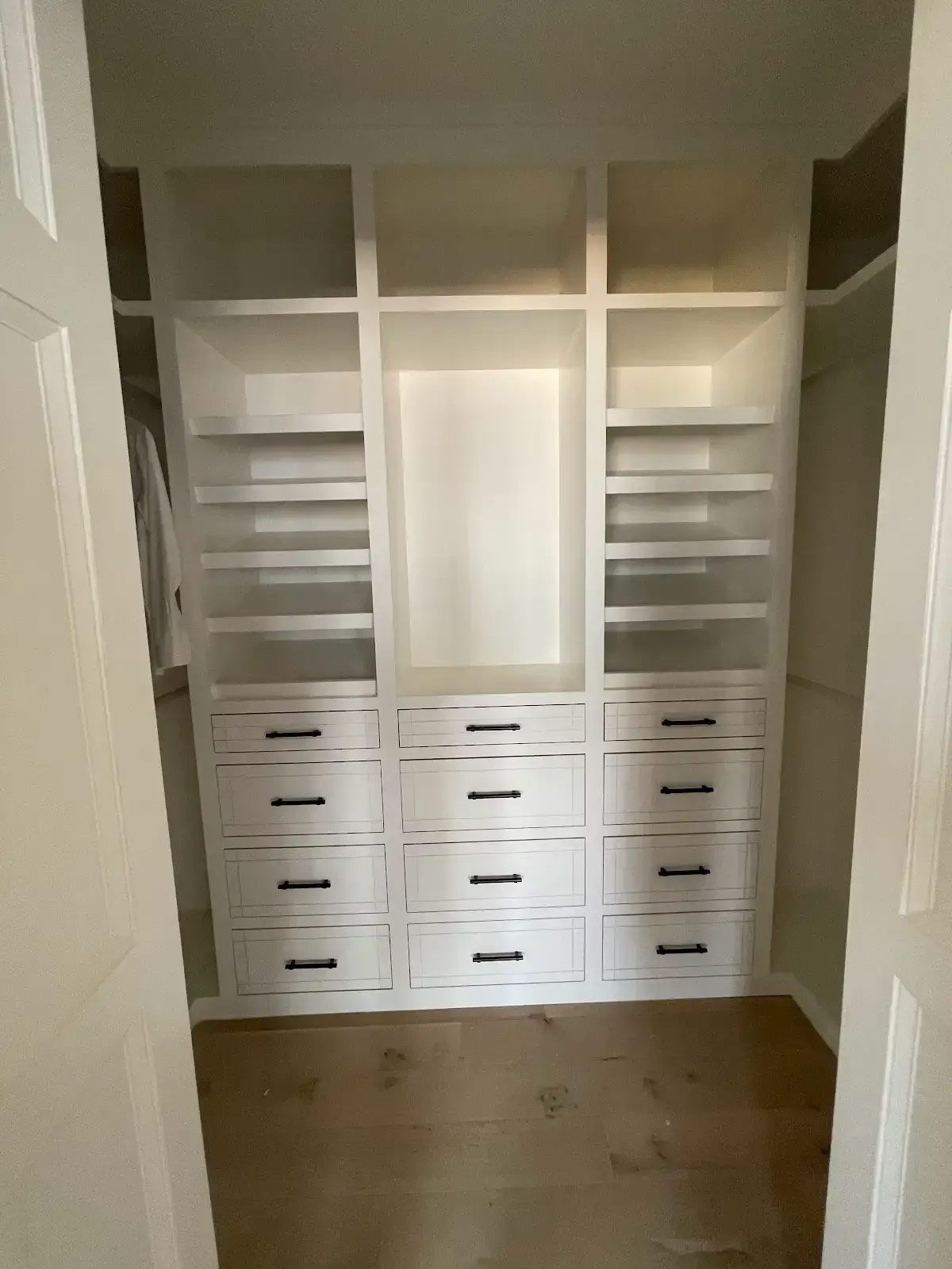 A walk in closet with lots of shelves and drawers