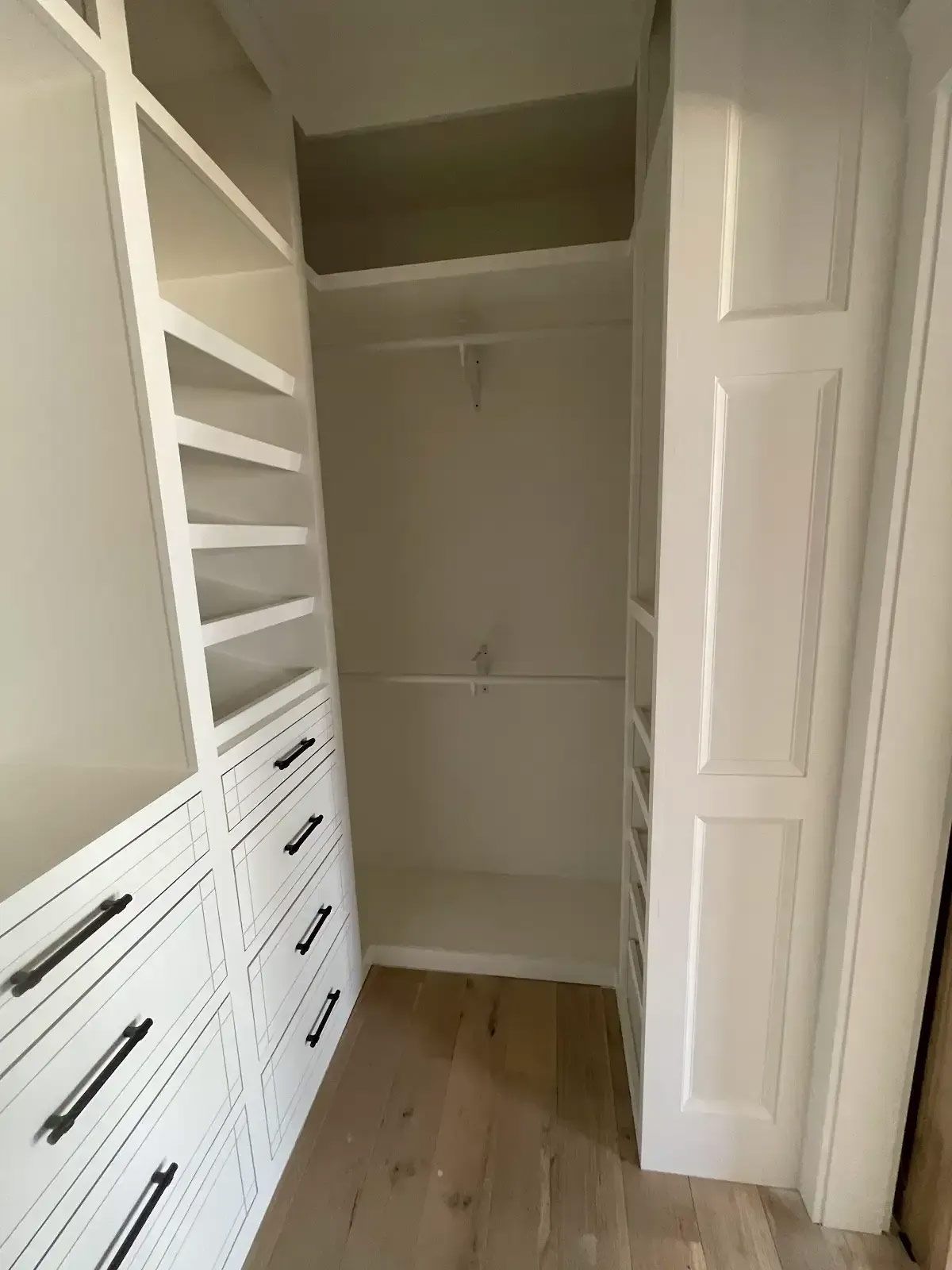 A walk in closet with lots of shelves and drawers