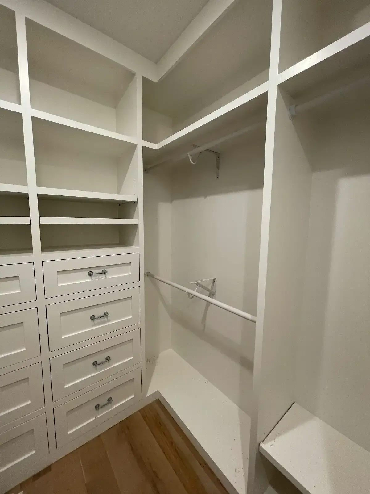 A walk in closet with lots of shelves and drawers