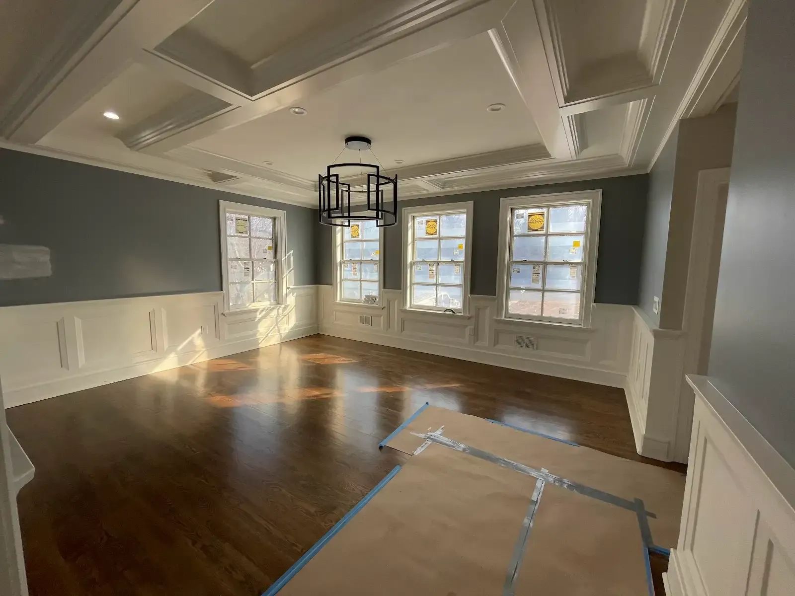 An empty living room with hardwood floors and a chandelier