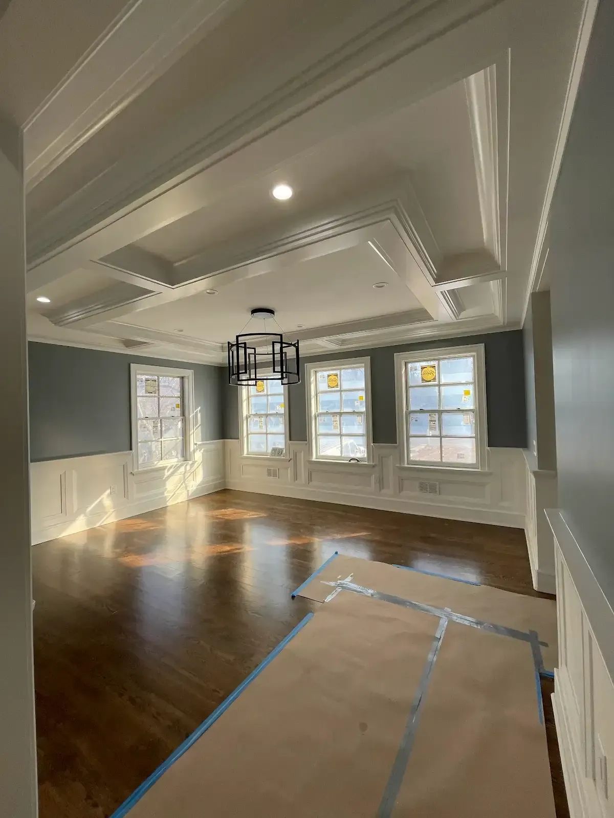 A large empty room with hardwood floors and a chandelier