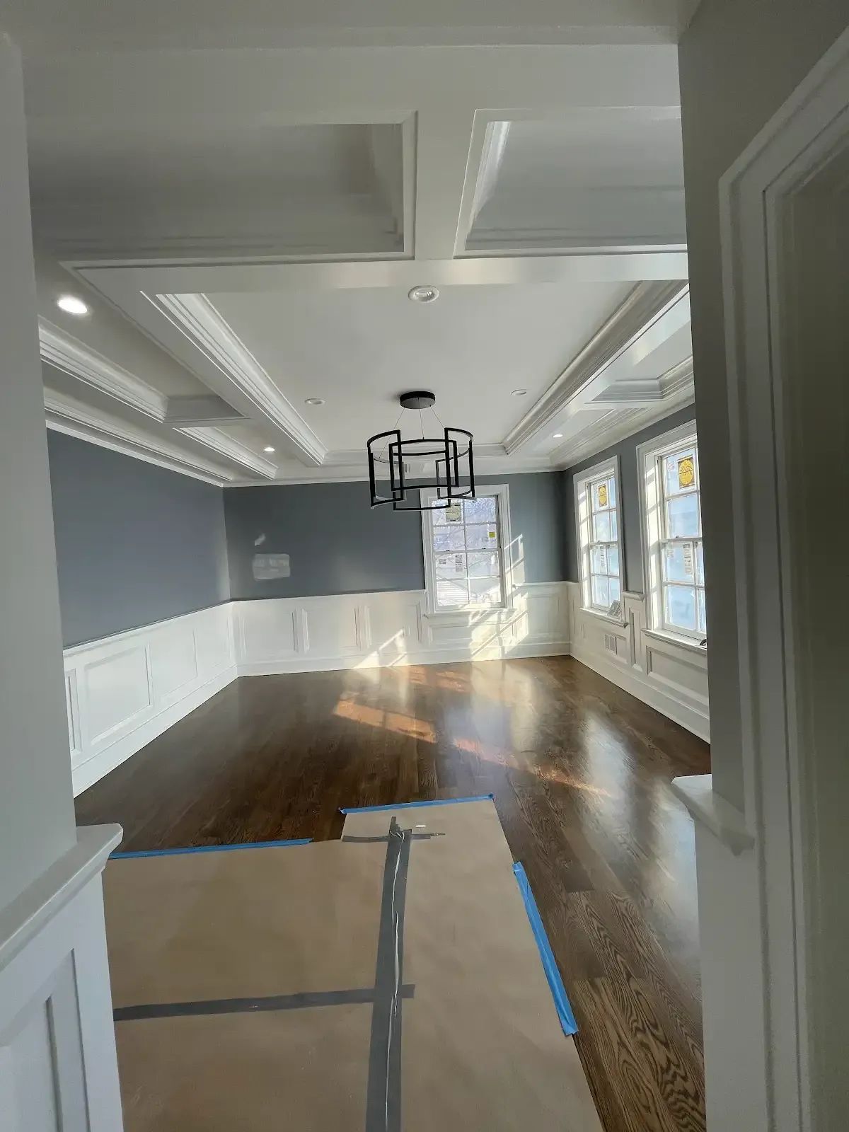 A large empty room with hardwood floors and a chandelier