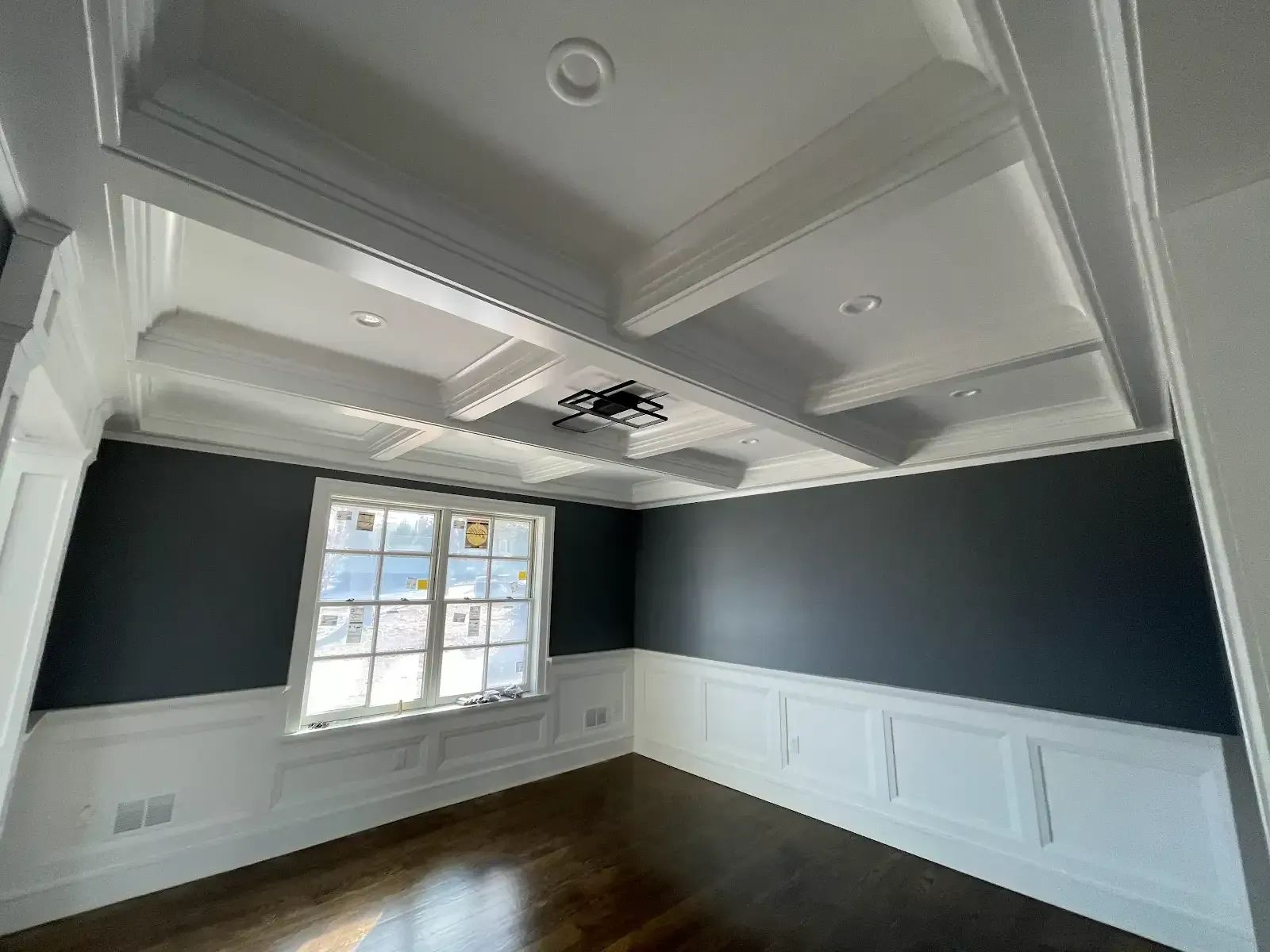 An empty room with a coffered ceiling and a window