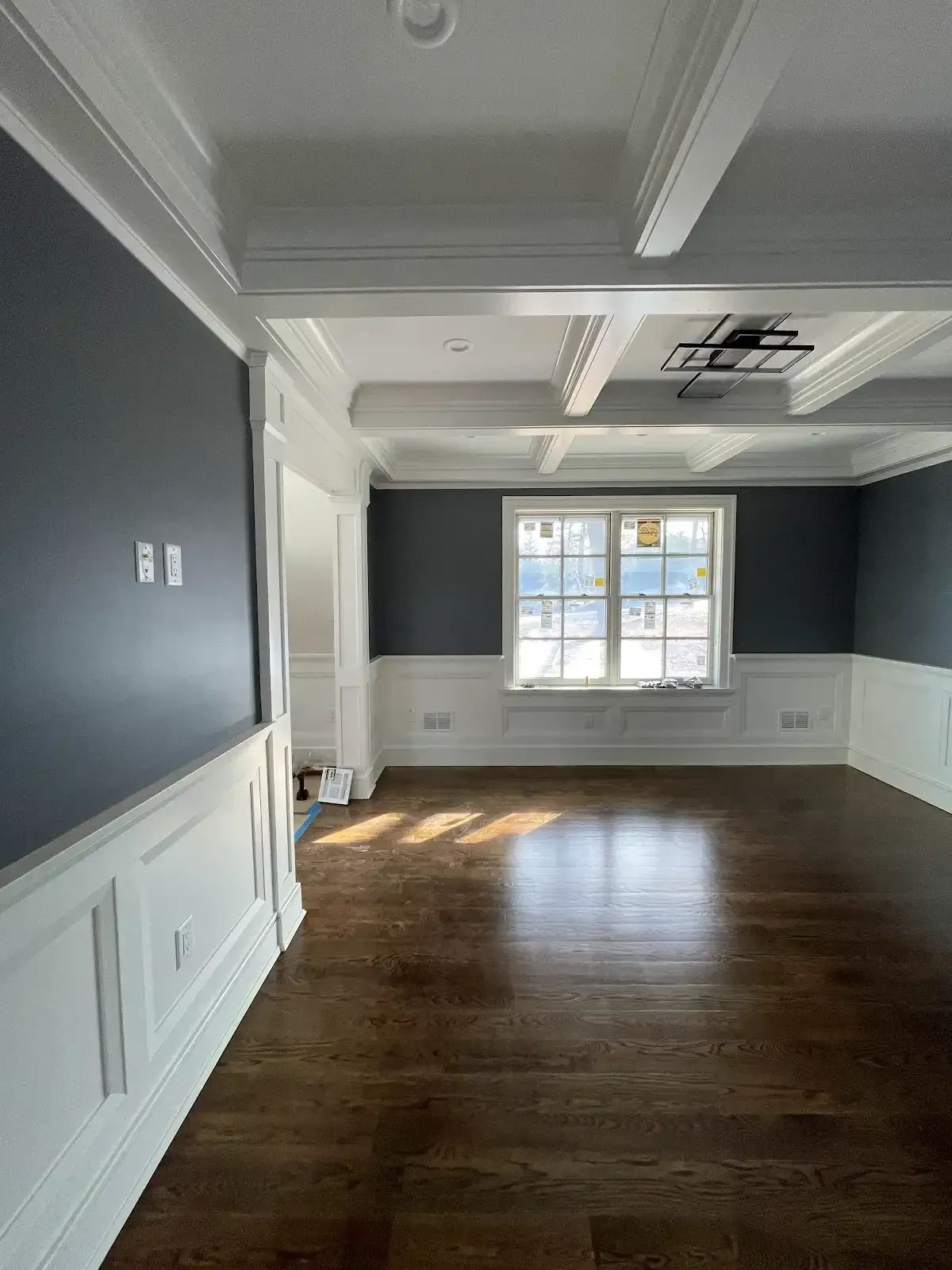 An empty living room with hardwood floors and a window