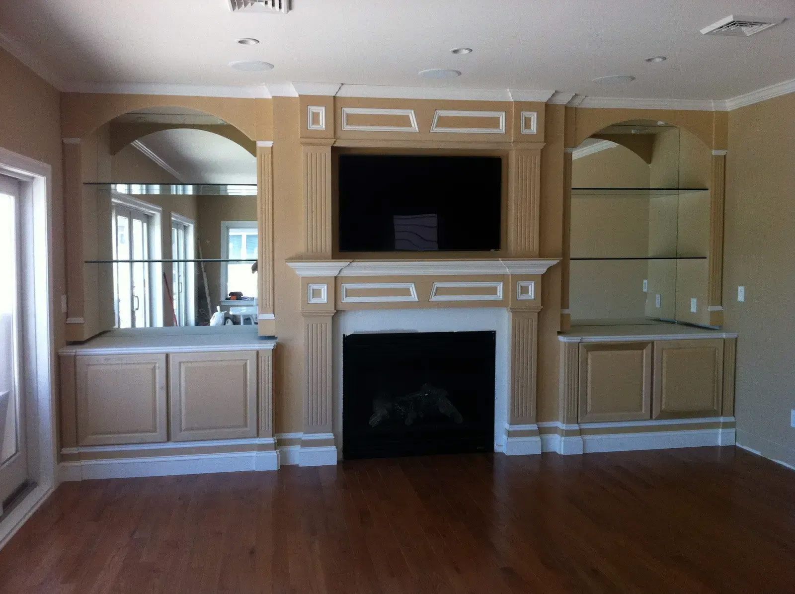 A living room with a fireplace, shelves, and a flat screen tv